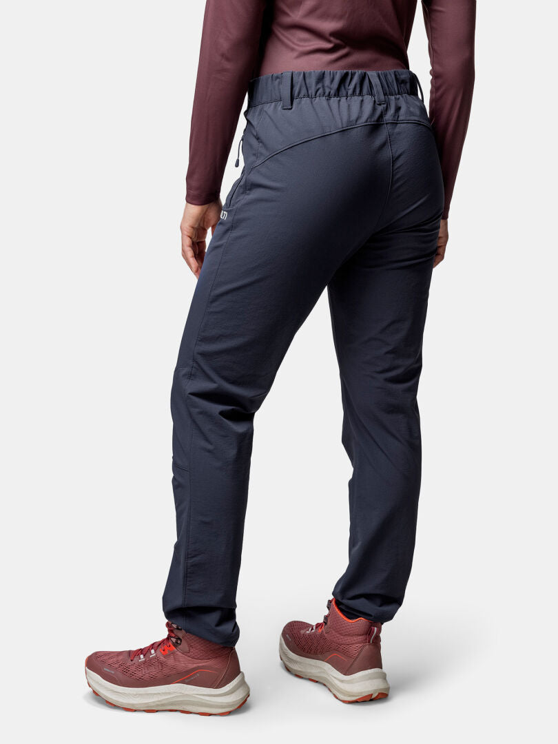 A woman in Halti Finholma X-stretch Pants, a maroon long-sleeve top, and red sneakers seen from the back.