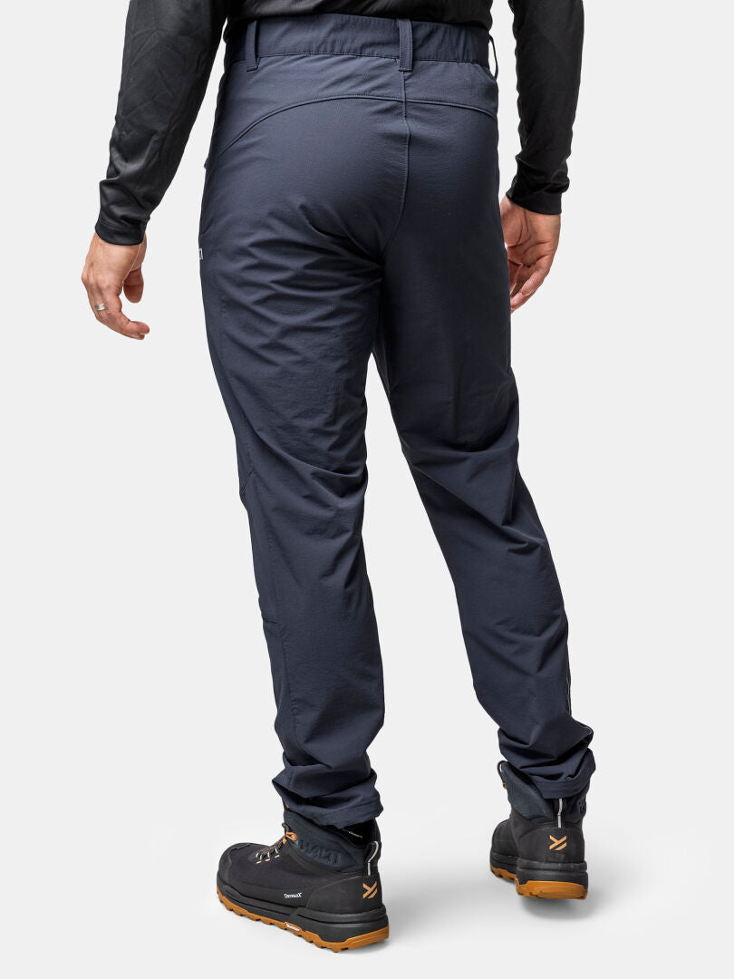 A person wearing Halti Finholma X-stretch Pants (mens), a black long-sleeve top, and black hiking boots, back view.