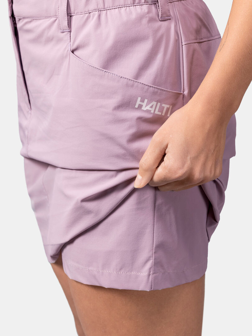 A person pinches the hem of light purple Halti Pallas Cool Skort, highlighting its stretchy, quick-drying fabric.