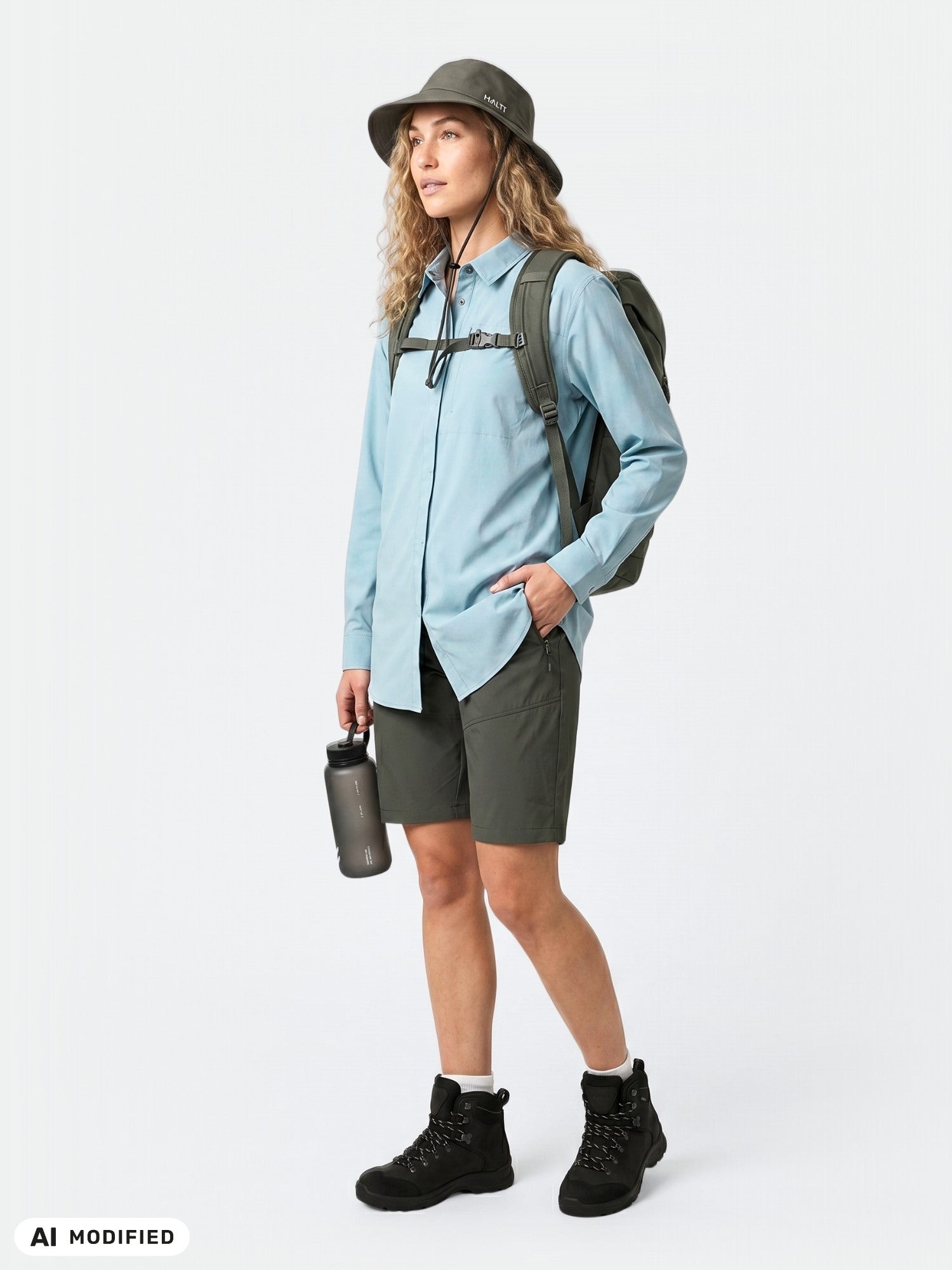 Woman in Halti Samoy Longsleeve Trekking Shirt, hat, backpack, and bottle; UPF 90+ outdoor protection.