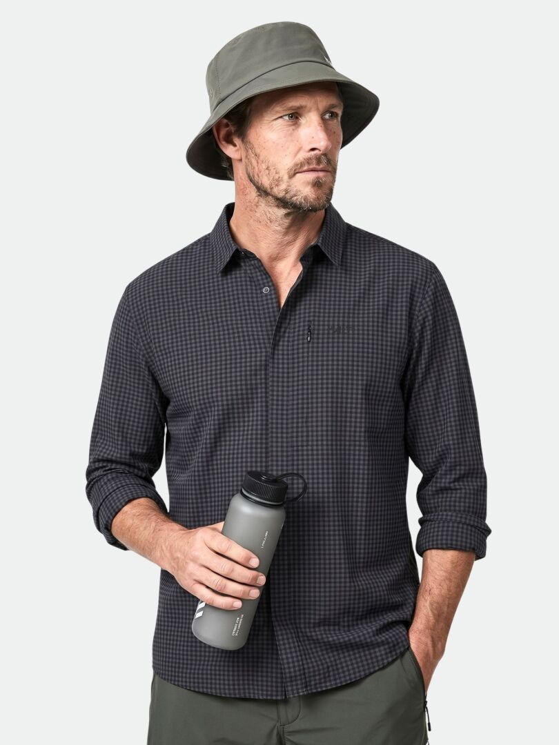 Man wearing Halti Samoy Longsleeve Trekking Shirt and bucket hat, holding a gray water bottle against a plain background.
