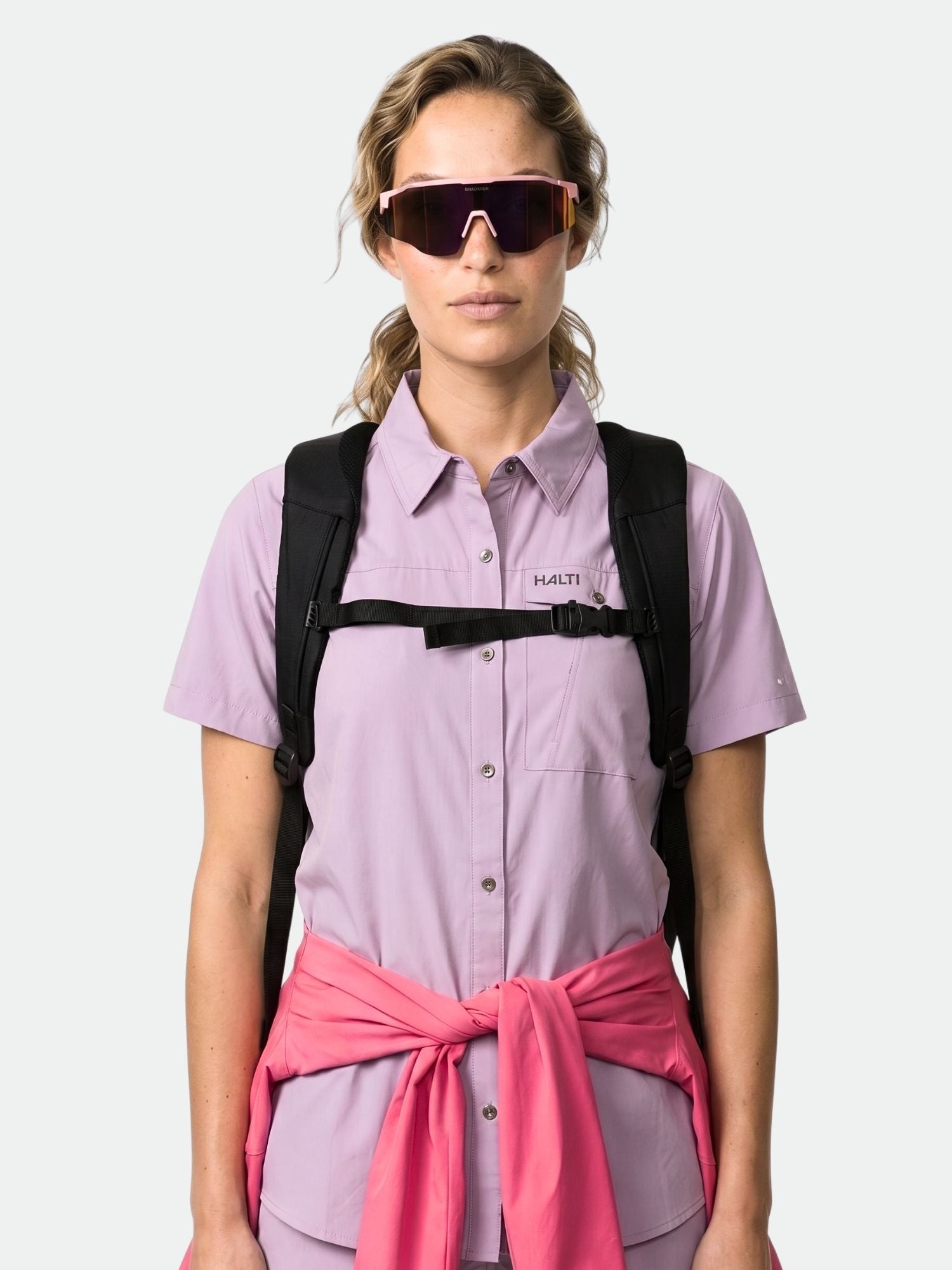 Wearing a Halti Samoy Trekking Shirt Women's, black backpack, pink sunglasses, and pink jacket tied at the waist.