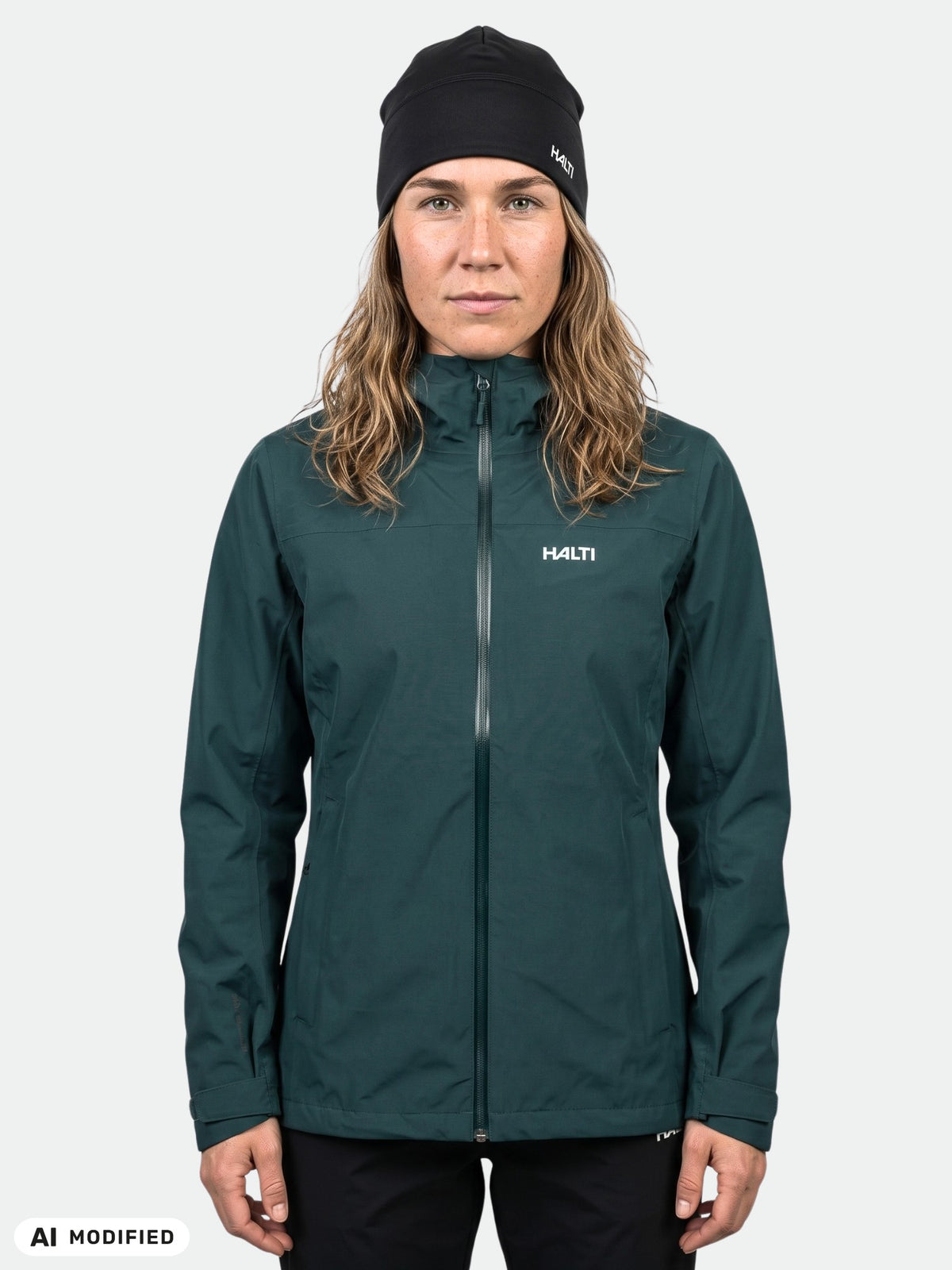 A woman wearing a dark green, breathable Halti Kaltimo DX Shell Jacket Women’s and a black beanie.