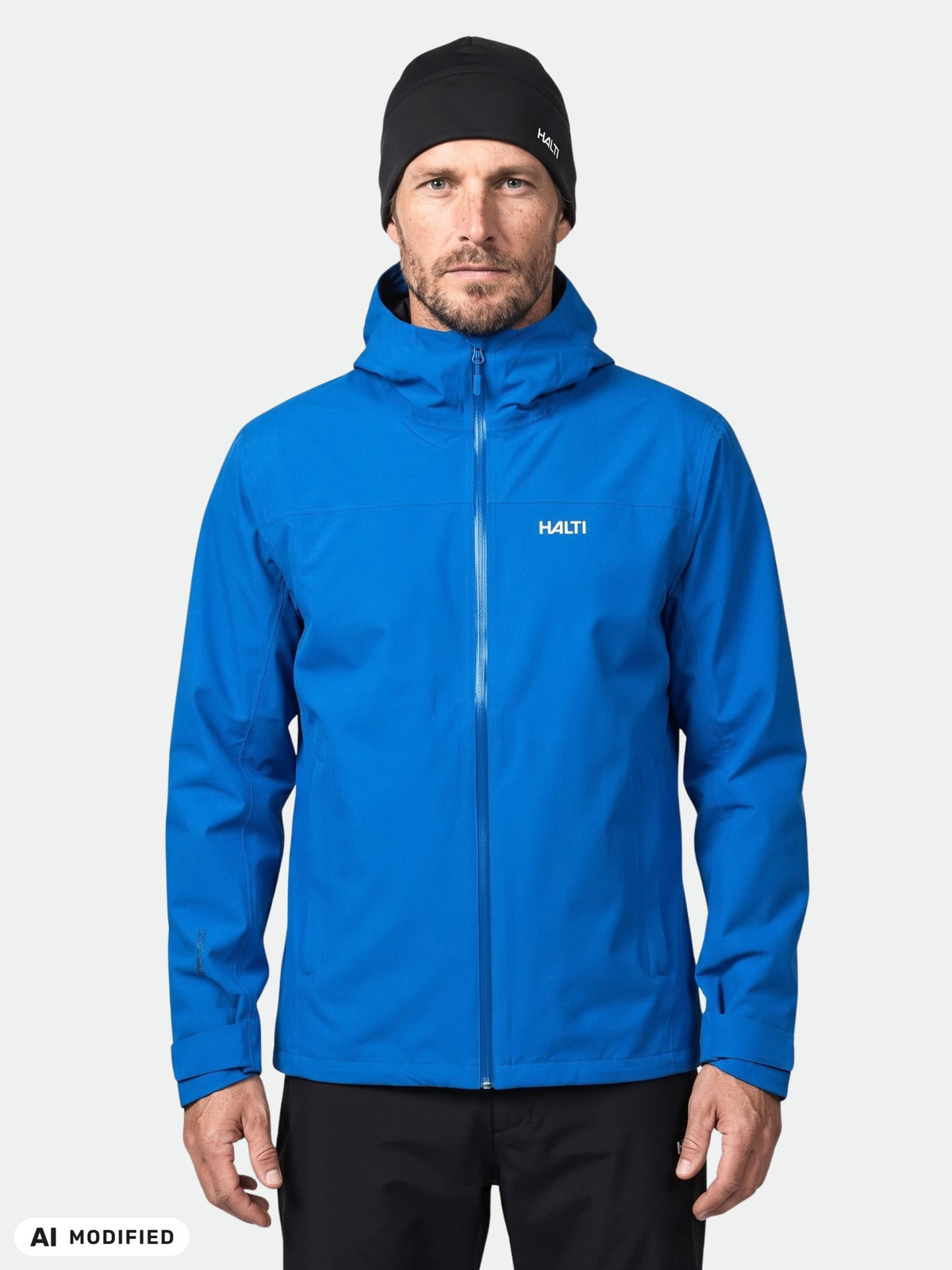 A man wearing a blue Halti Kaltimo DX Shell Jacket and a black beanie.