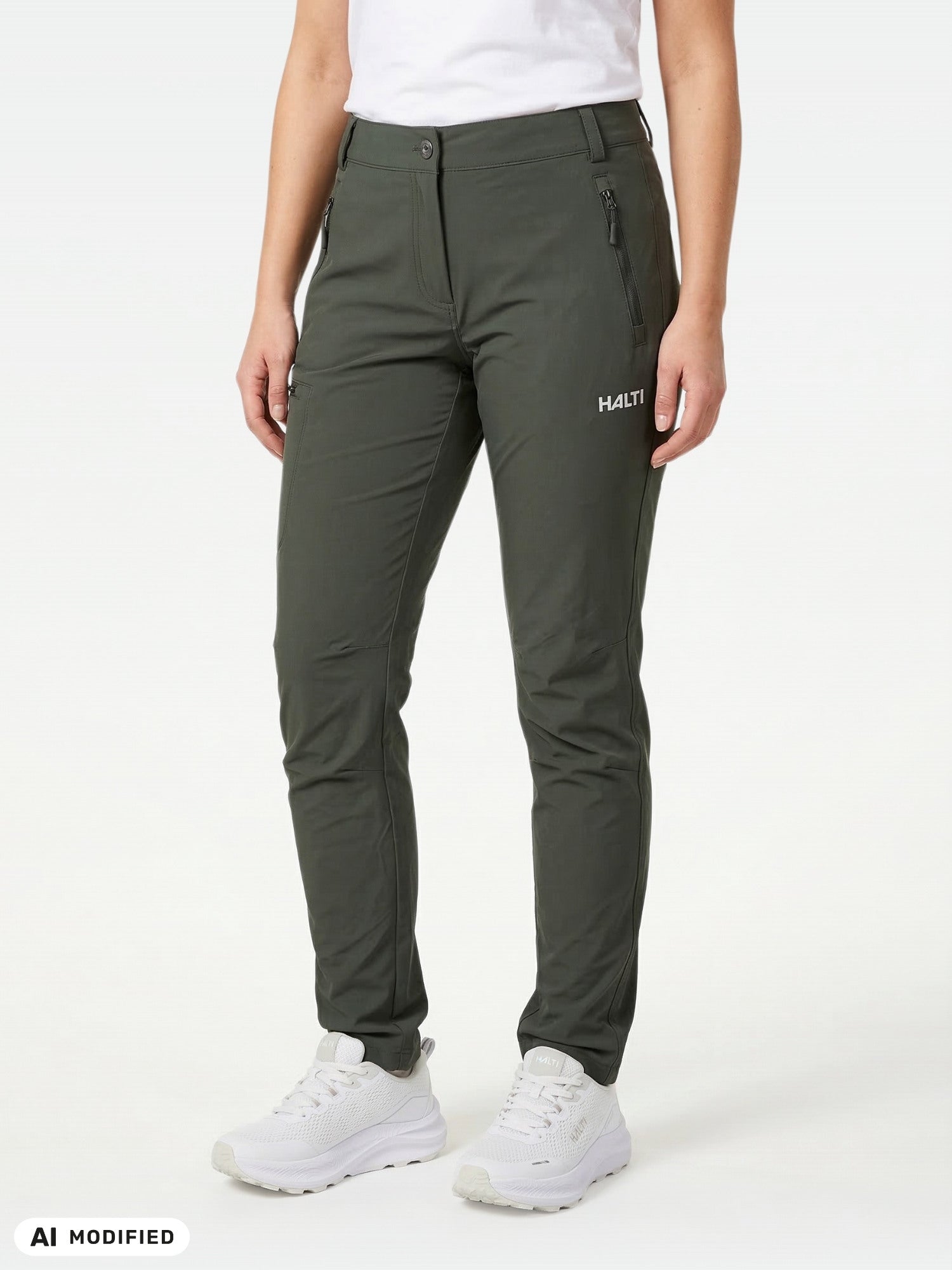 She wears Halti Pallas X-stretch Outdoor Pants, white sneakers, and a shirt, standing against a plain background.