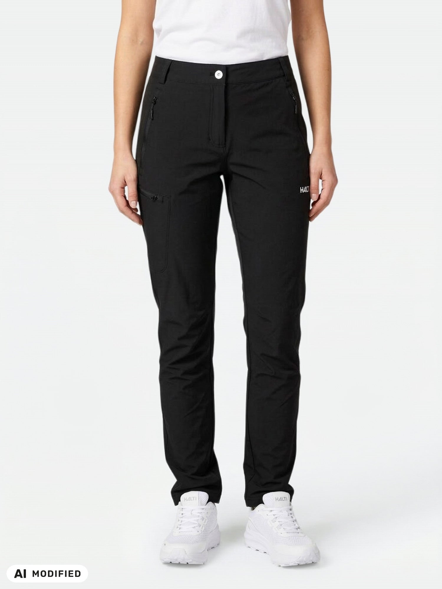 Woman in Halti Pallas X-stretch Outdoor Pants and white sneakers, posed stylishly against a plain light background.