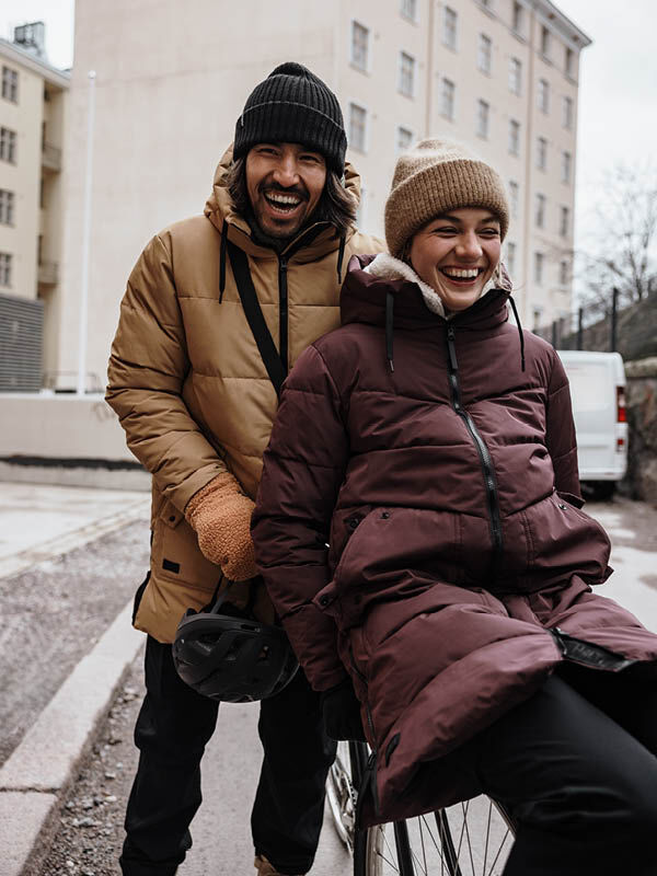 Two women in winter coats smile outdoors; one wears the Halti Linjat Parka Jacket while the other stands behind.