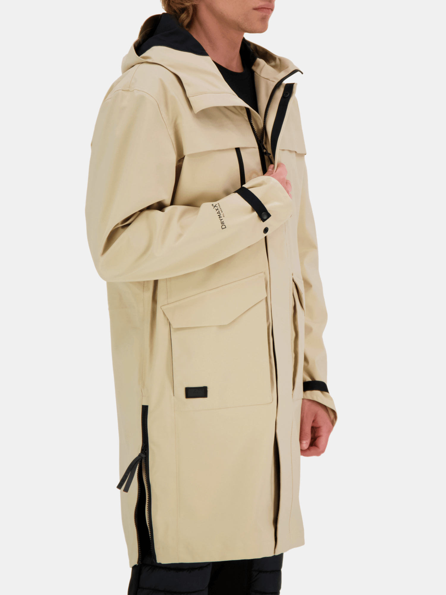 A person in the Halti Tokoi Mens DrymaxX Parka Jacket, beige with black zippers and large front pockets, side view.