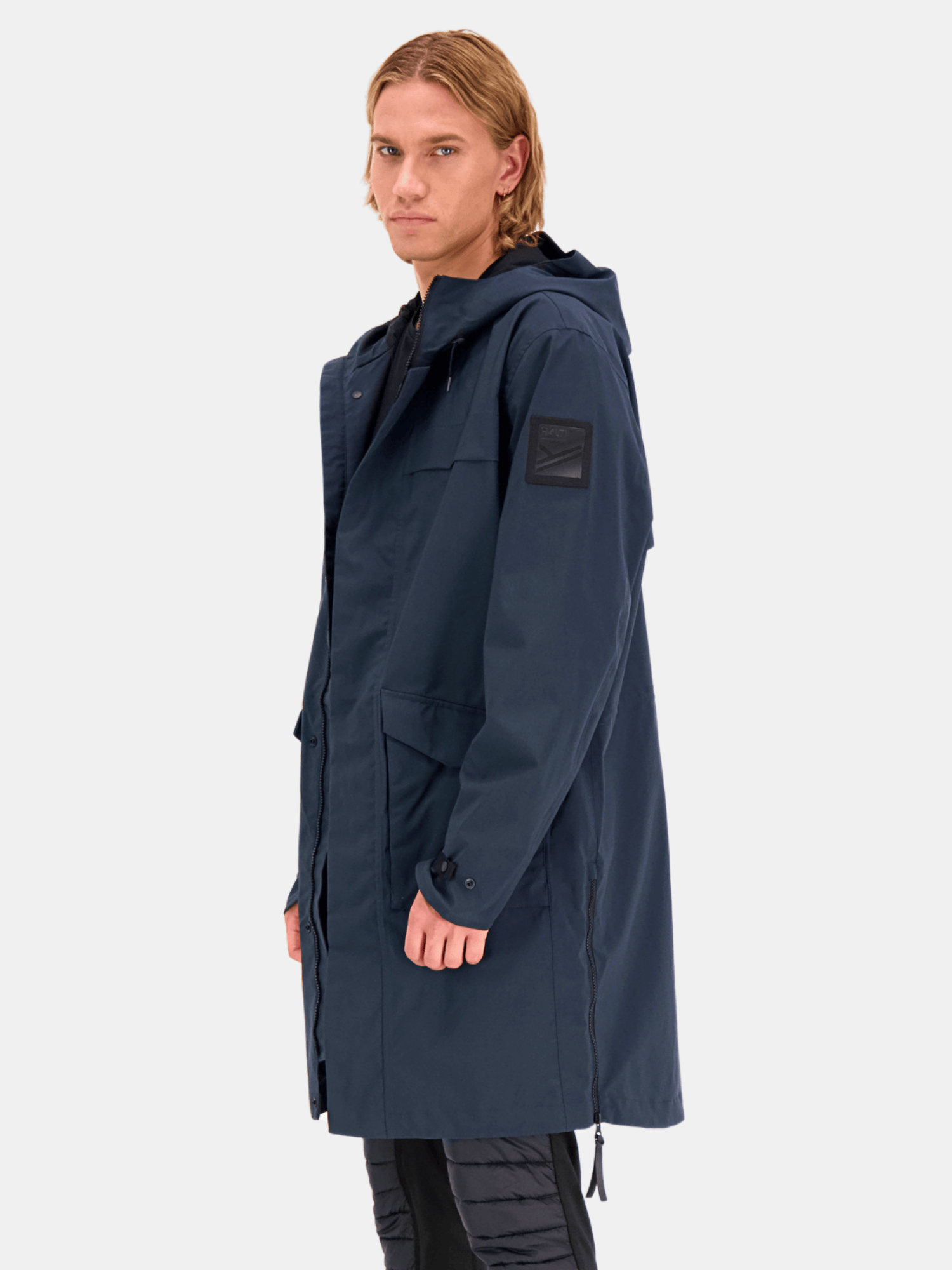 Person wearing a Halti Tokoi Mens DrymaxX Parka Jacket in navy blue with large pockets, against a plain light background.