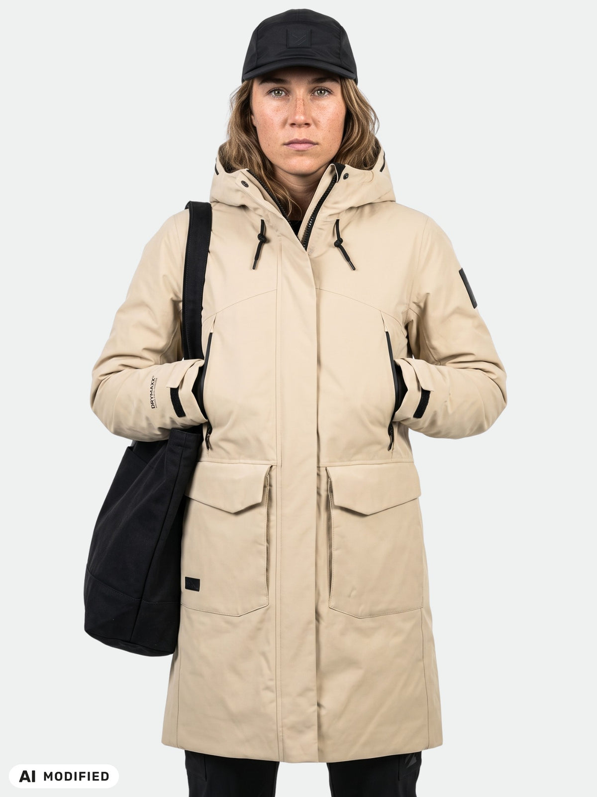 A person wearing a beige waterproof Halti Bergga DX Winter Parka with large front pockets and a black shoulder bag.