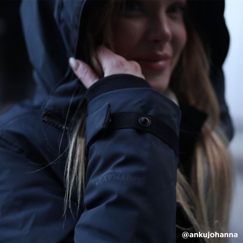 A woman in a Halti Bergga Womens DrymaxX Winter Parka holds the hood near her face, long hair visible.