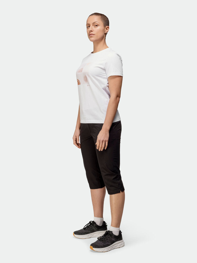 Person standing slightly to the side, wearing a Halti Matka T-shirt Womens, black capri pants, and black sneakers.