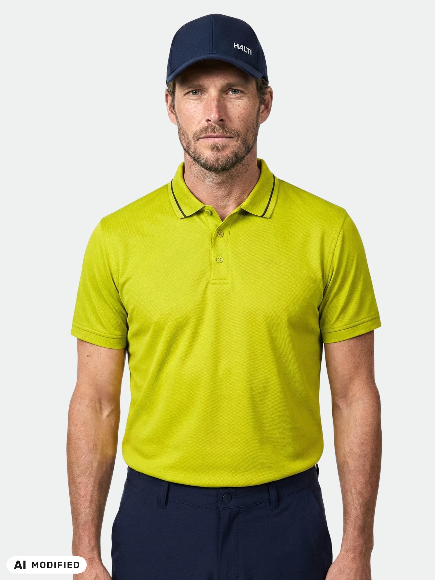 Man wears Halti Laine Technical Polo Shirt and navy cap, facing forward with neutral expression against plain background.
