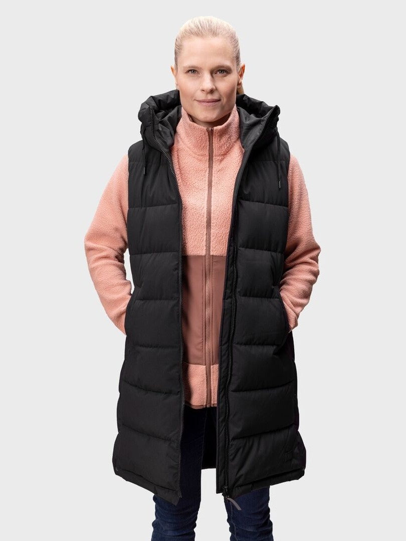 A woman wears the Halti Penger Puffer Vest over a pink zip-up fleece jacket and jeans, facing forward.
