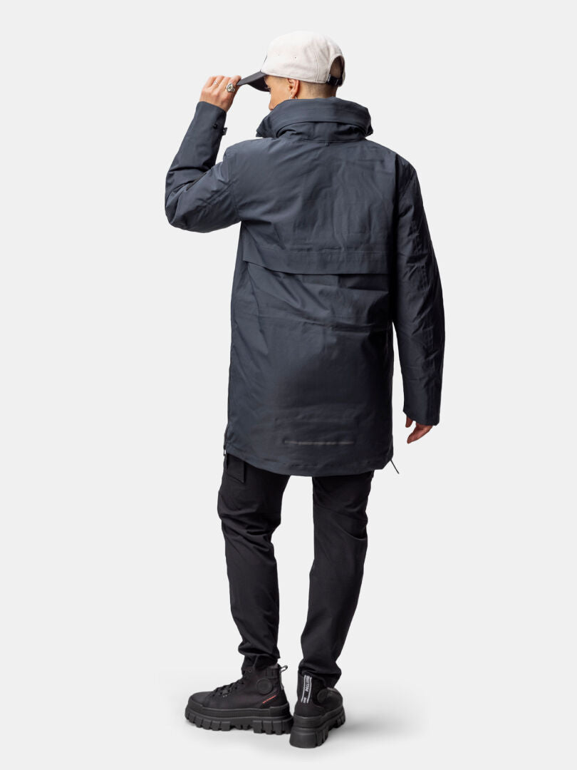 Person wearing the Halti Synkas 3in1 DrymaxX Parka Women's, black pants, boots, and adjusting a white baseball cap.