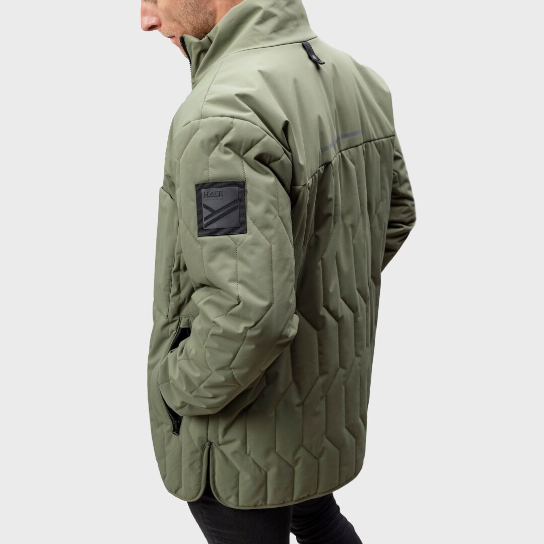 A person in a light olive green Halti Synkas 3in1 DrymaxX Parka with black patches and innovative monomaterial design.