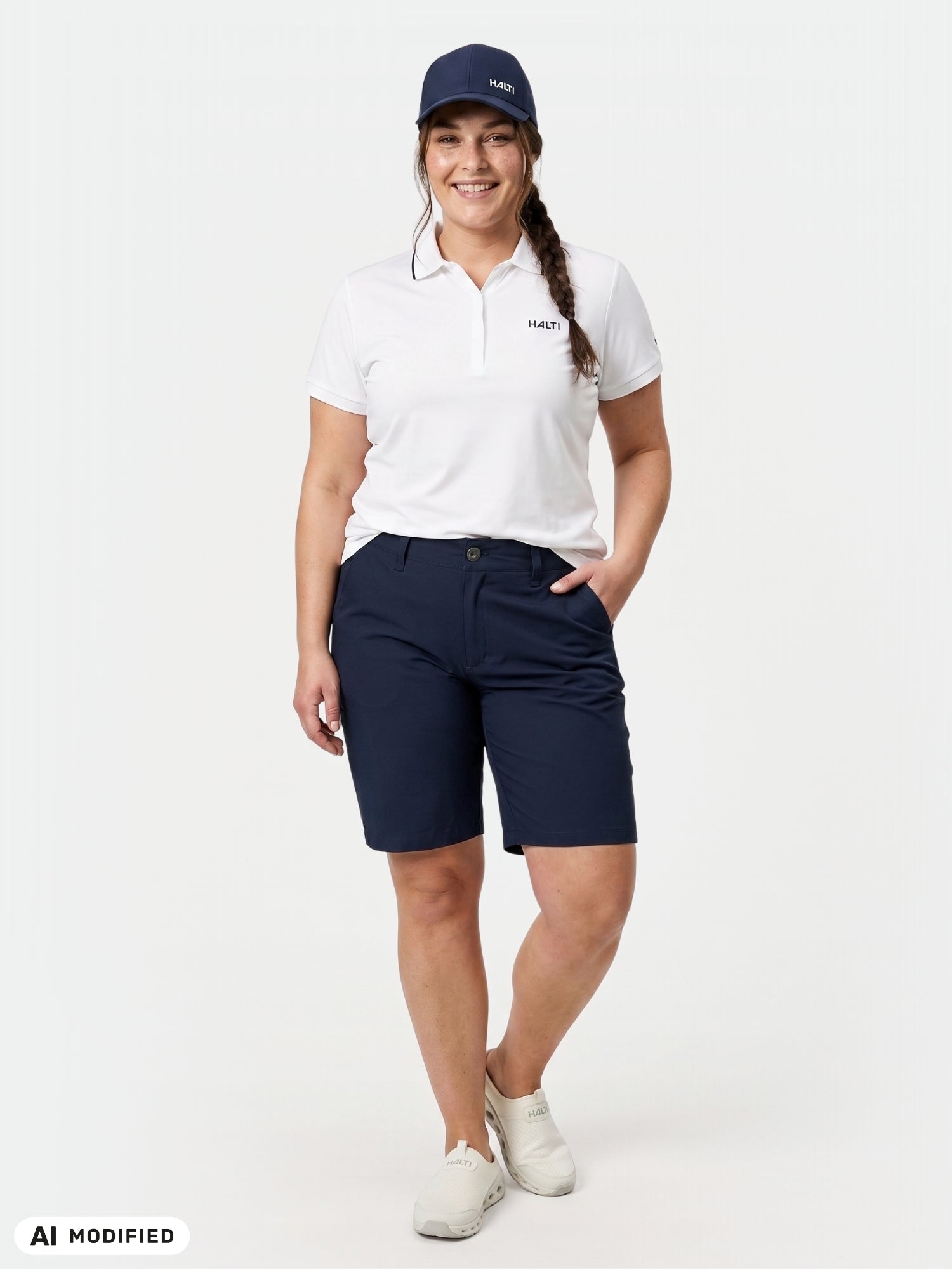 A person in Halti Drive X-stretch Shorts Women's Plus, a white polo, and UPF 50+ navy cap stands against a white background.