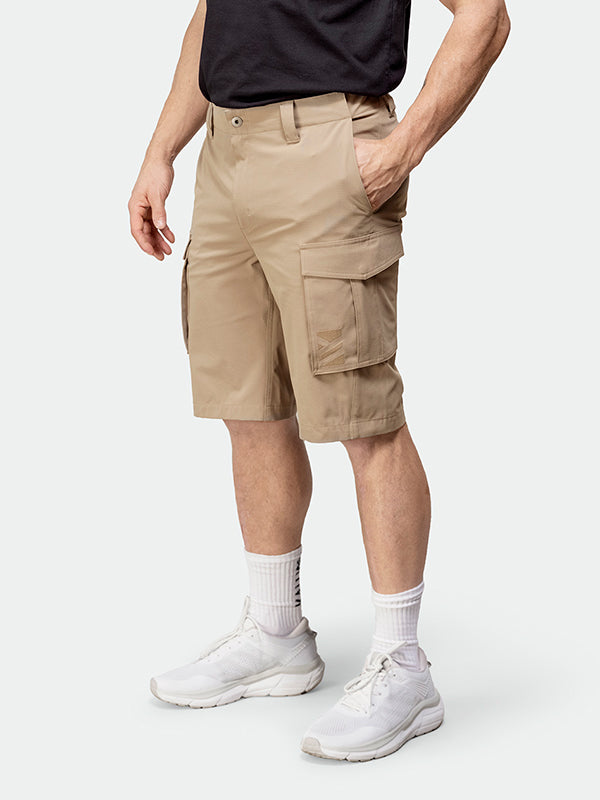 A person wears Halti Roams Shorts Mens in tan, a black shirt, white socks, and sneakers against a plain background.