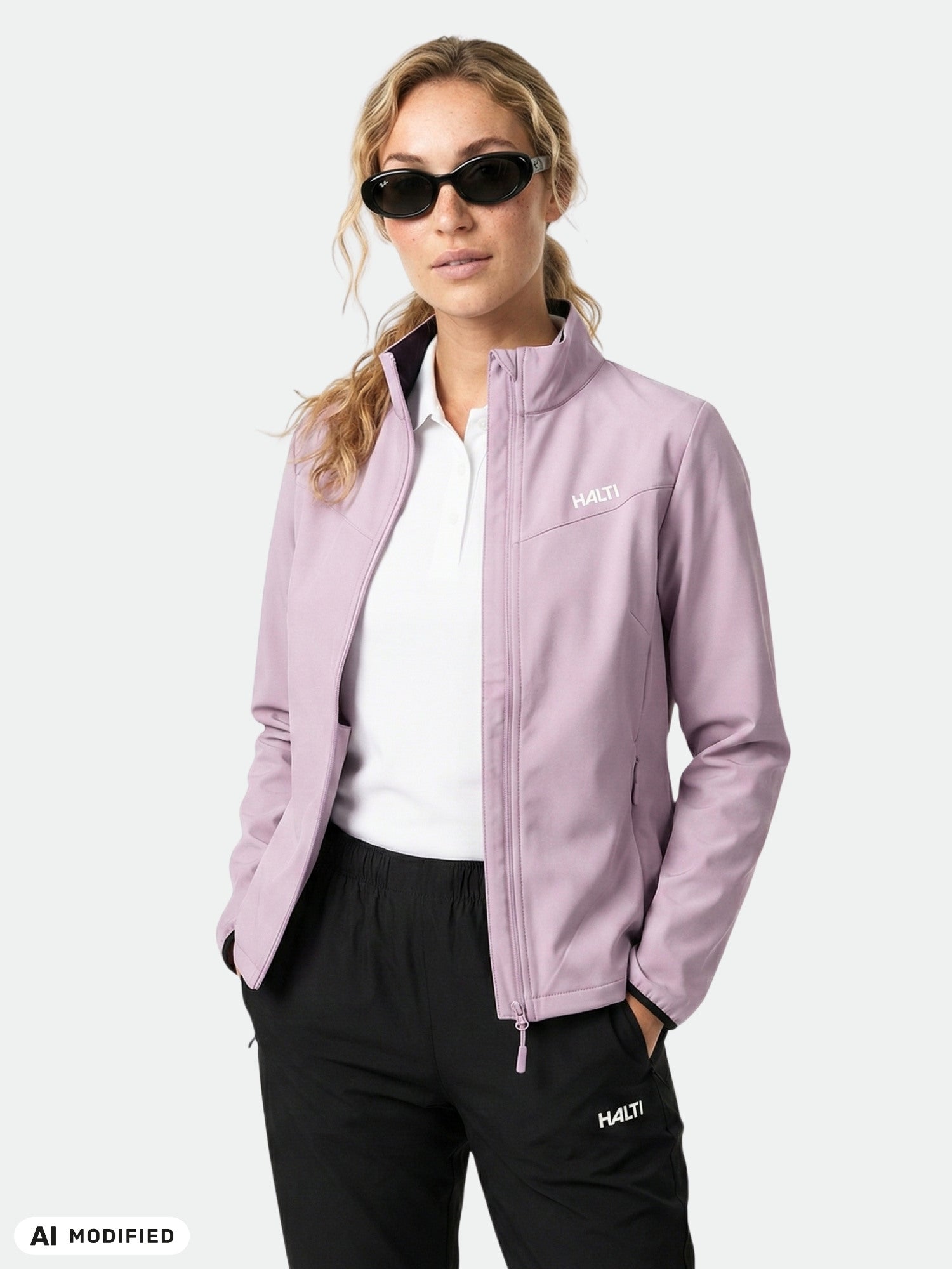 Woman in Halti Wedge Softshell Jacket, light purple, windproof, recycled polyester; white shirt, black pants, plain backdrop.