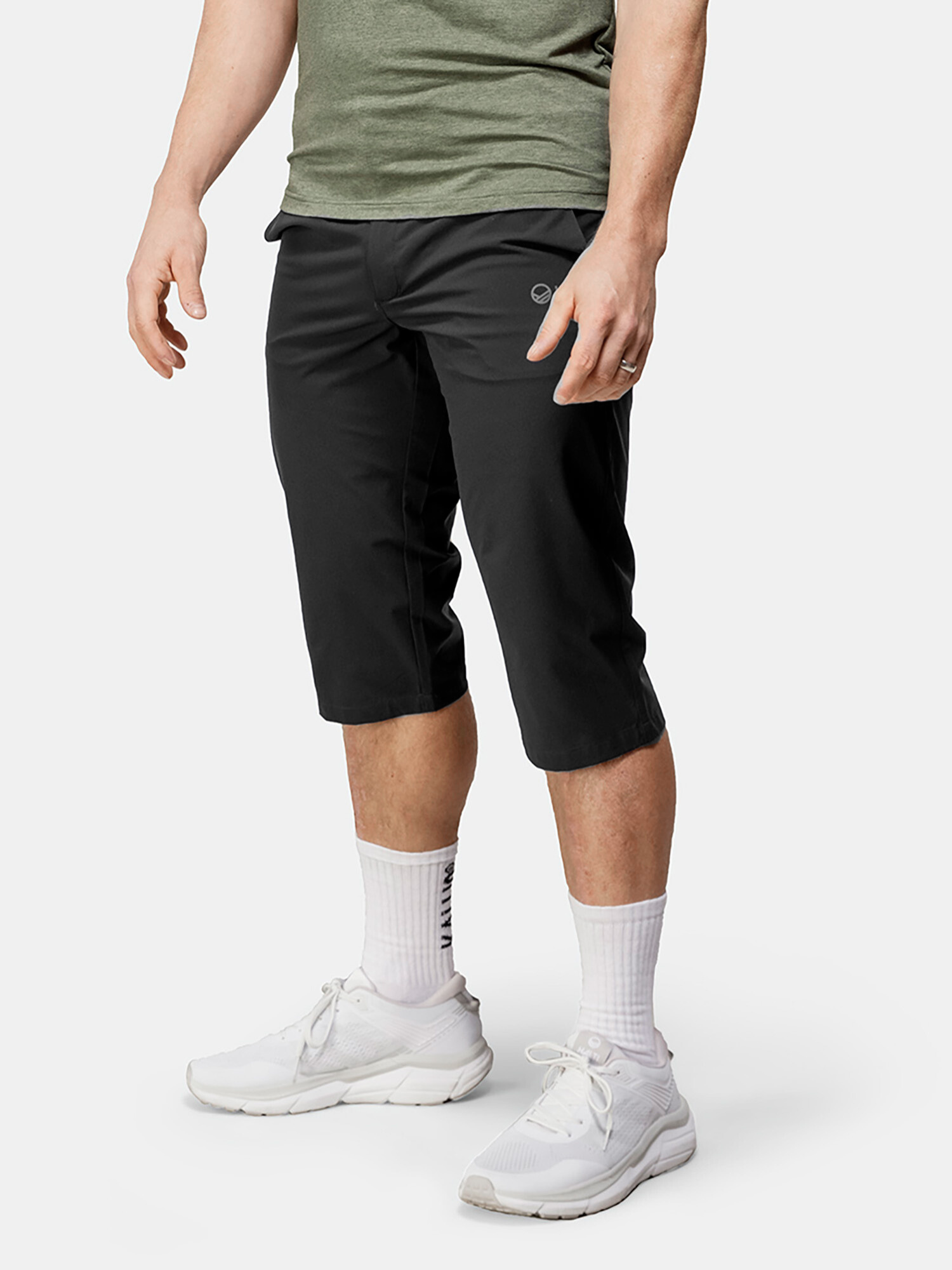 A person wears Halti Drive X-stretch Capri Pants with a green t-shirt, white socks, and sneakers against a plain background.