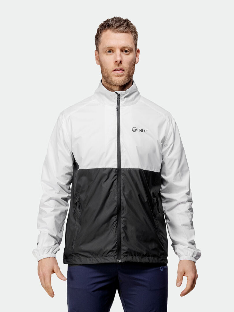 Man wears Halti Saime Windbreaker Jacket—white top, black bottom, recycled materials, HALTI logo on chest.