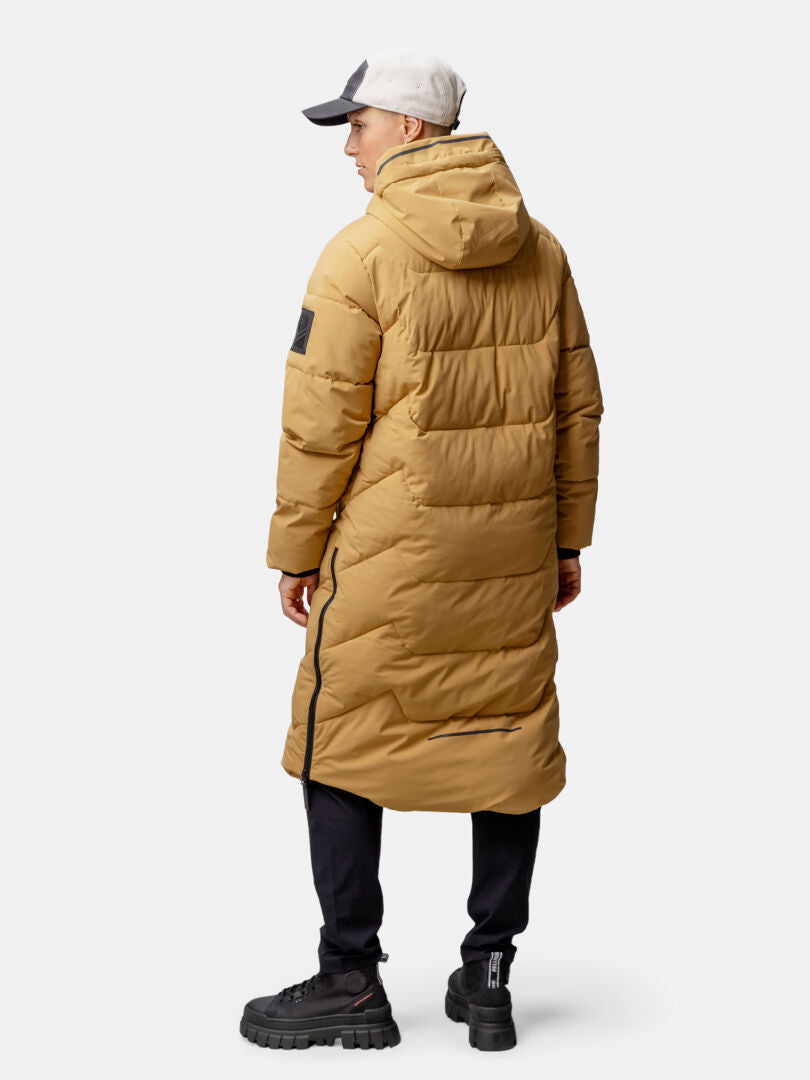 A person in the Halti Brahe Puffer Long Winter Jacket for women, black pants, and a cap, shown from the back.