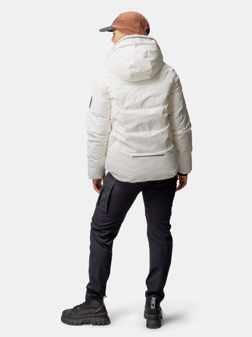 Person in a white Halti Brahe Puffer Winter Jacket, black pants, and brown cap stands with back to camera.