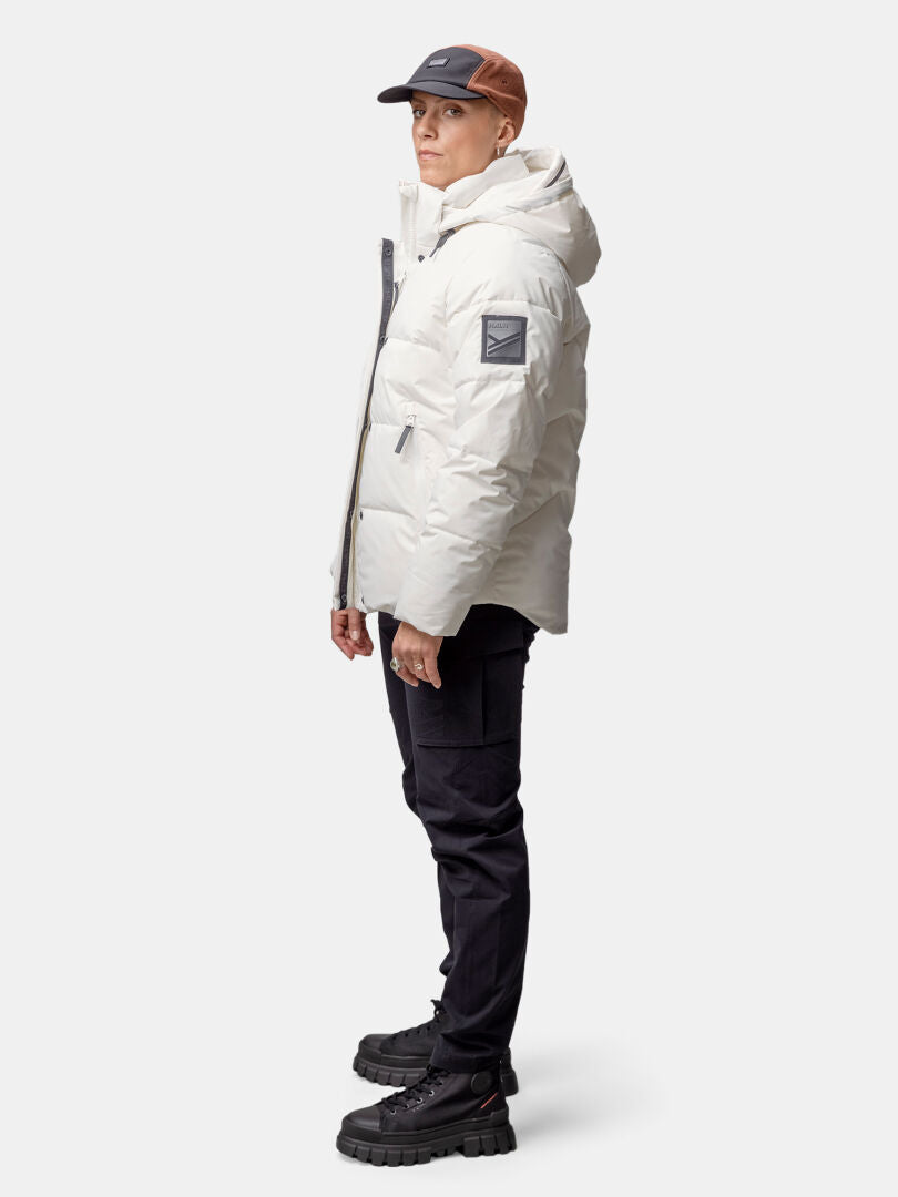 Person in Halti Brahe Puffer Winter Jacket for women, white, recycled polyester, with dark pants and two-tone cap.