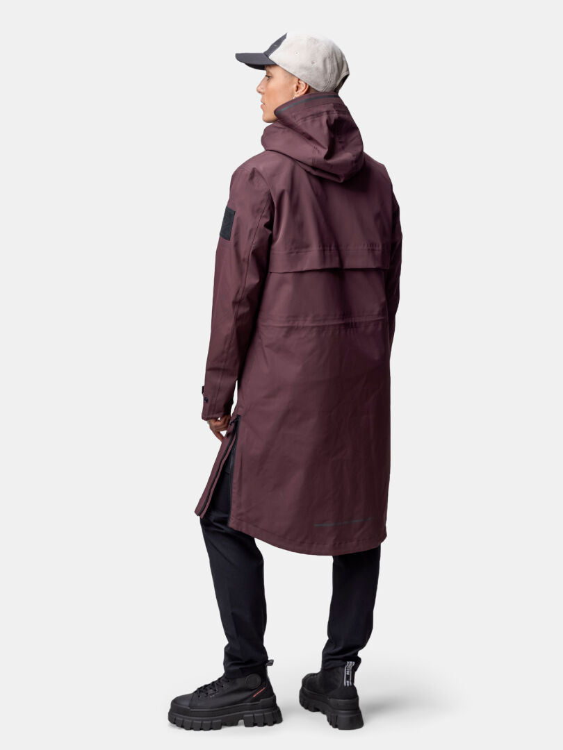 Person wearing a Halti Tokoi II DX Parka Jacket Womens in maroon, with black pants, shoes, and a light gray cap, facing away.