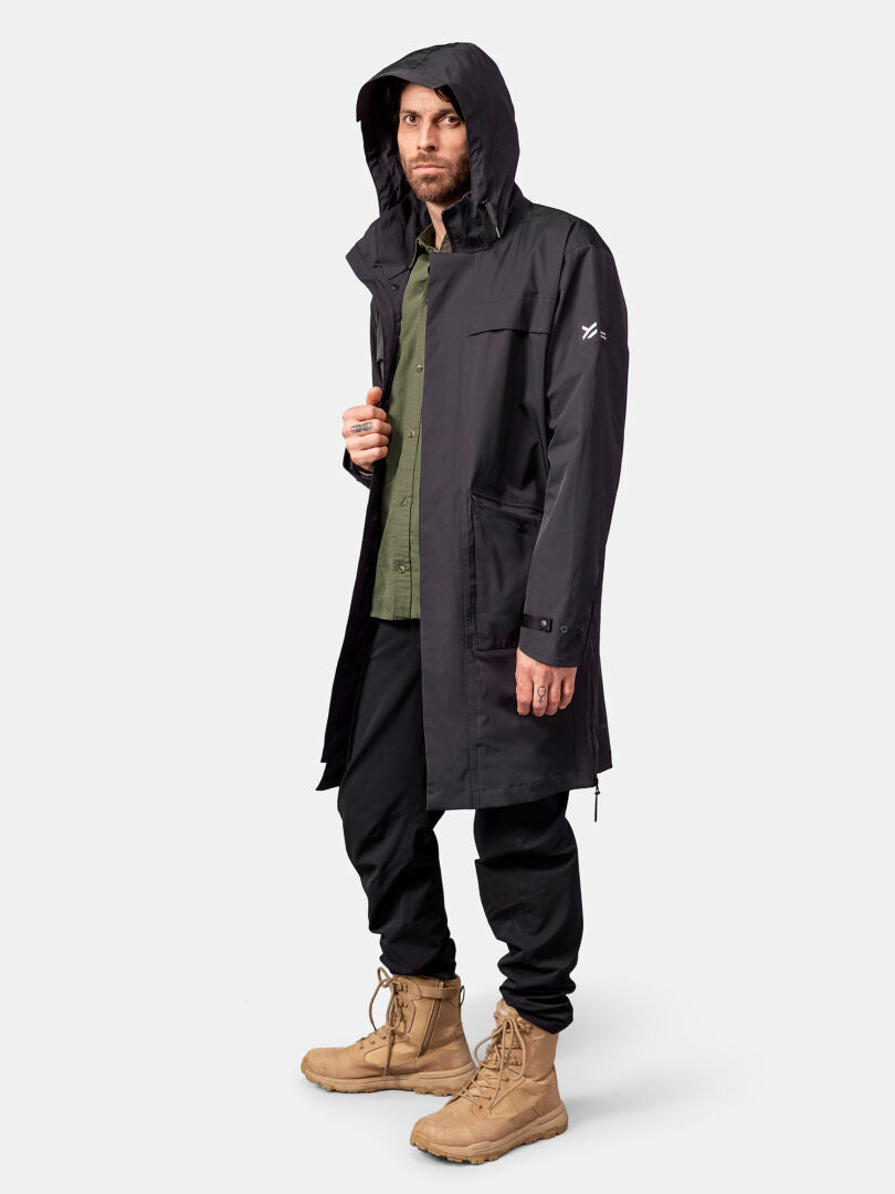 A man wears the Halti Tokoi II DX Parka Jacket, green shirt, black pants, and tan boots against a white background.
