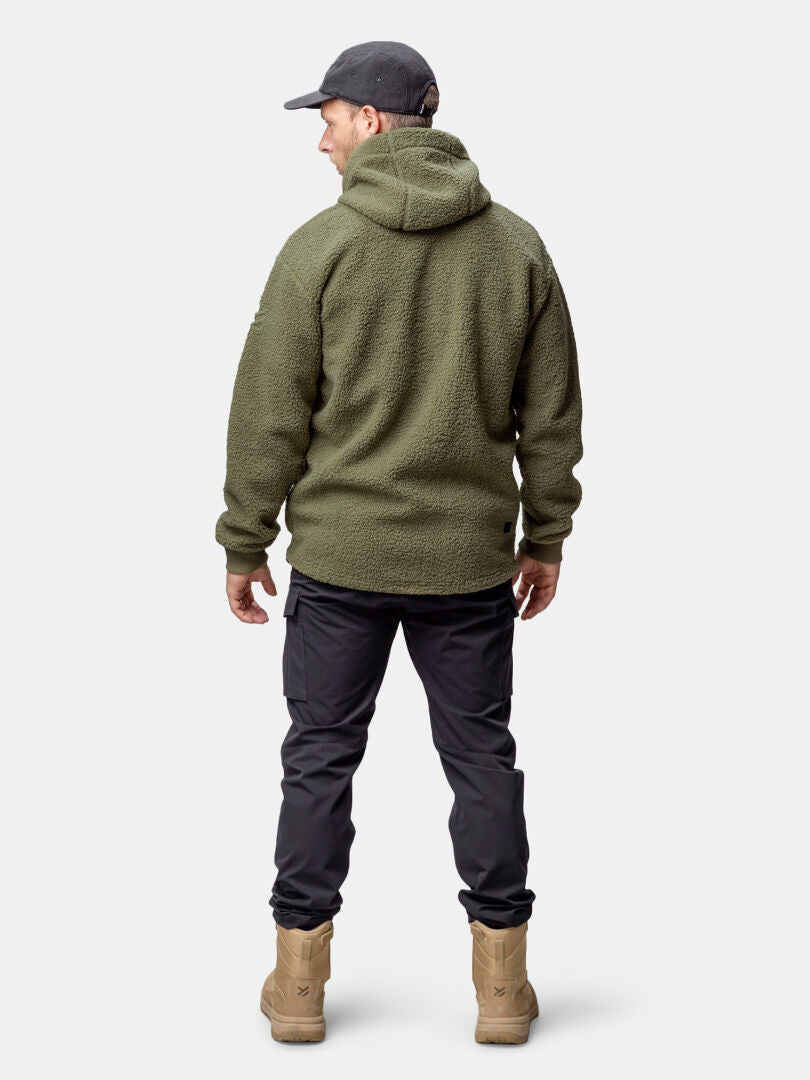 A man in a Halti Lykky Fleece Jacket (mens), black cargo pants, tan boots, and dark cap stands facing away.