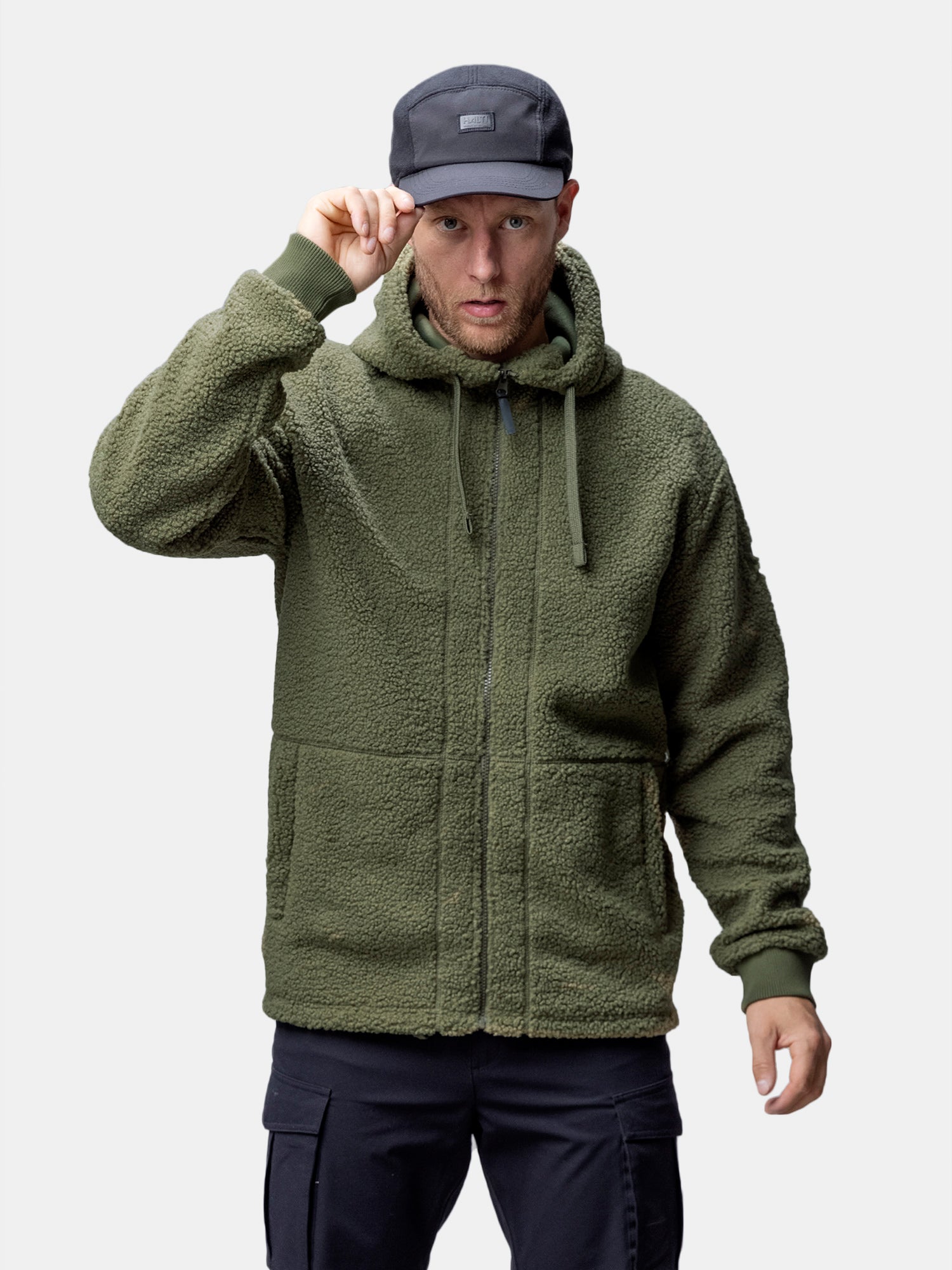 Man in a Halti Lykky Fleece Jacket for men with hoodie-inspired fleece and black cap, touching his brim.