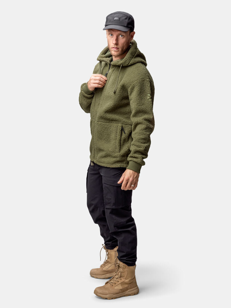 A man in the Halti Lykky Fleece Jacket, black cargo pants, and tan boots stands against a plain background.