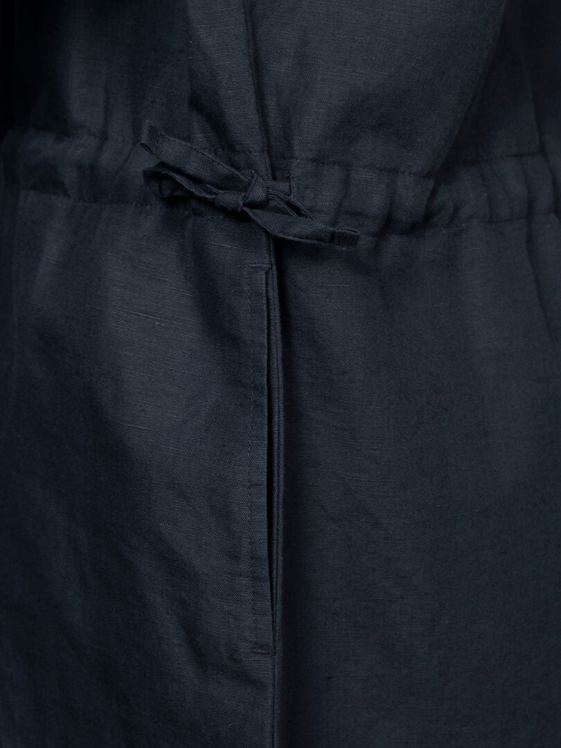 Close-up of Halti Notsgi Dress Women's, a dark organic cotton dress with a drawstring bow at the waist.