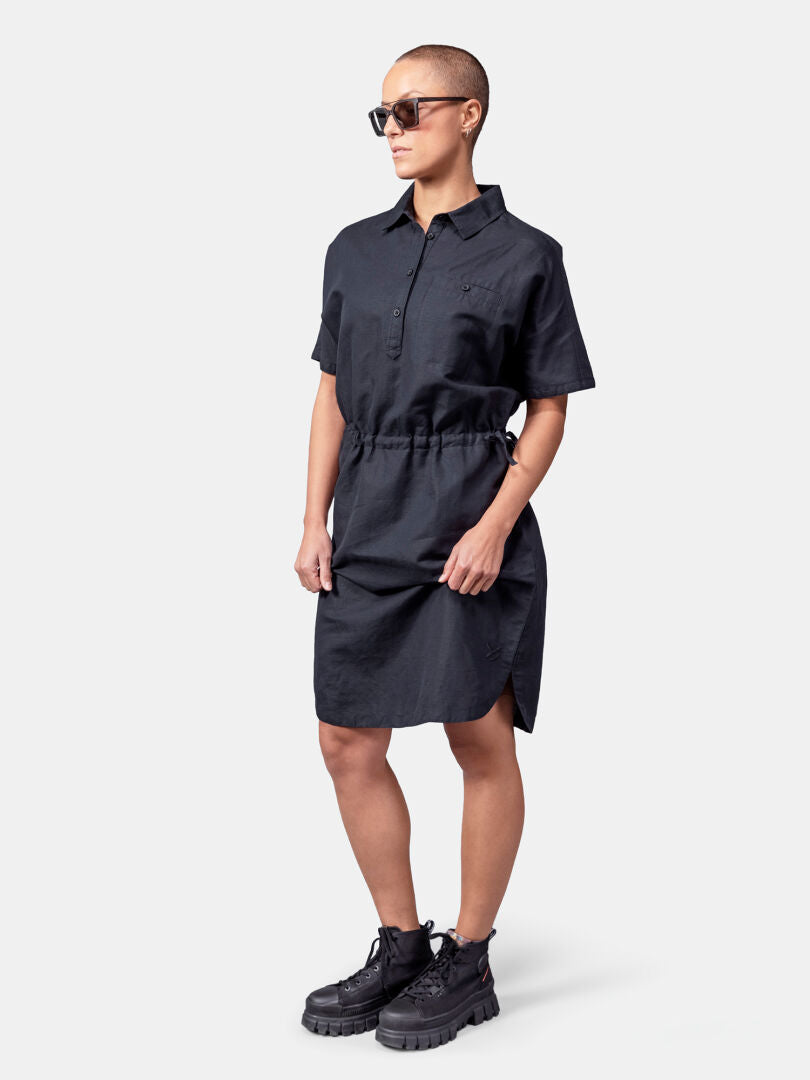Woman in Halti Notsgi Dress, sunglasses, and black boots stands against a plain background.