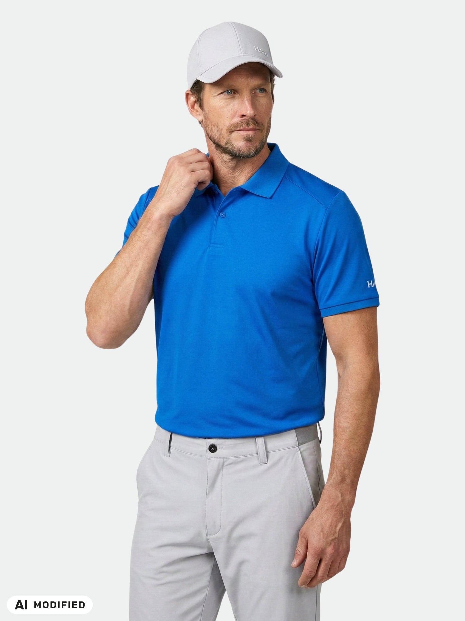 Man in Halti Aridi Technical Polo Shirt, light gray pants, and white cap stands against a plain background.