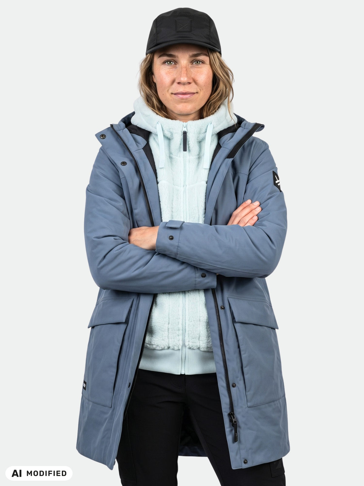 Model wears Halti Kortteli DX Insulated Parka Women’s, light blue fleece, and black cap against a plain backdrop.