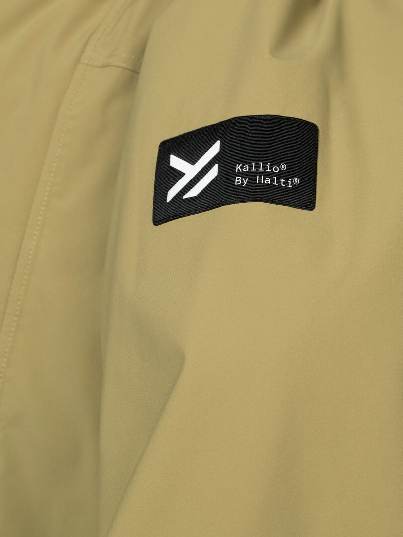 Close-up of the beige Kortteli DX Insulated Parka Men’s with a black Halti patch and white geometric logo.