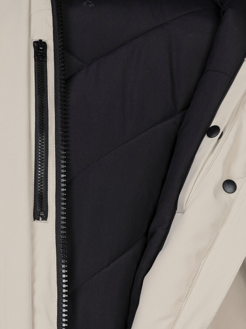 Halti Kallio DX Parka Women’s in beige with black zipper, padded lining, and snap buttons for outdoor performance.