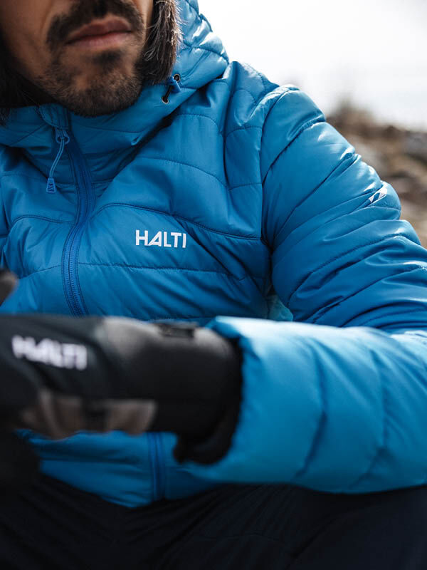 Person wearing a Halti Huippu Down Jacket Men’s and gloves outdoors, face and upper body partially visible.