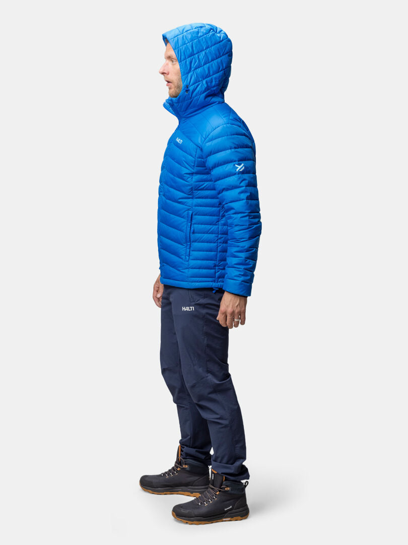 A man wears the Halti Huippu Down Jacket Men’s with navy pants and black boots, standing in profile.