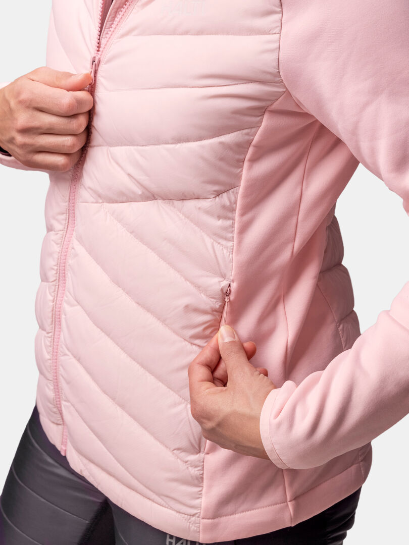 A woman zips the side pocket of a pink Halti Huippu Hybrid Down Jacket with matching sleeves and Pertex Quantum fabric.