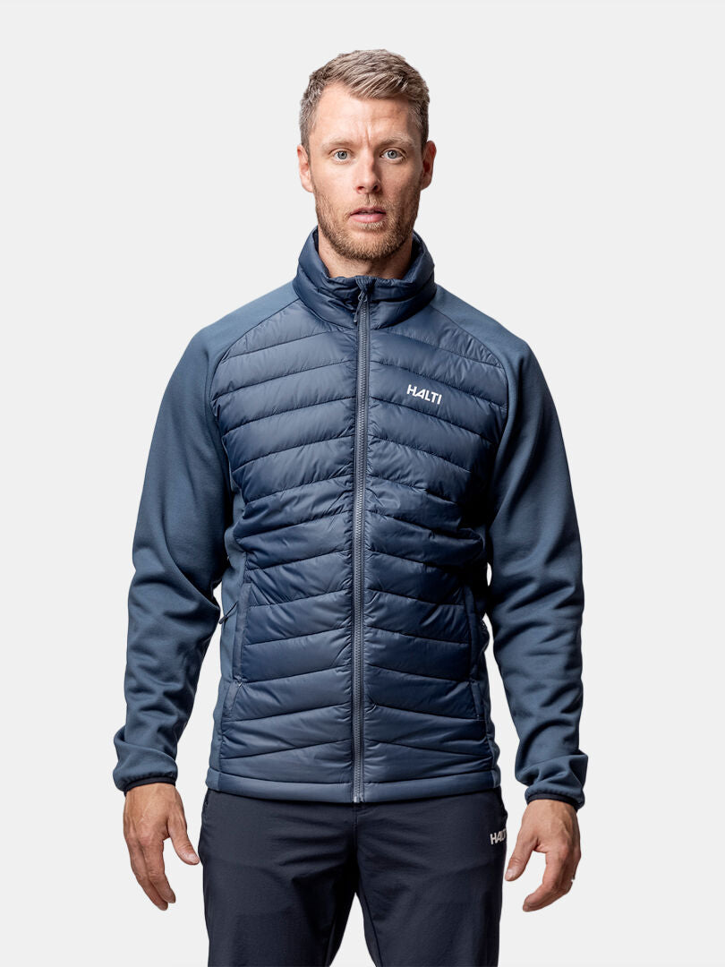 A man wears the Halti Huippu Hybrid Down Jacket for men, standing against a plain white background.