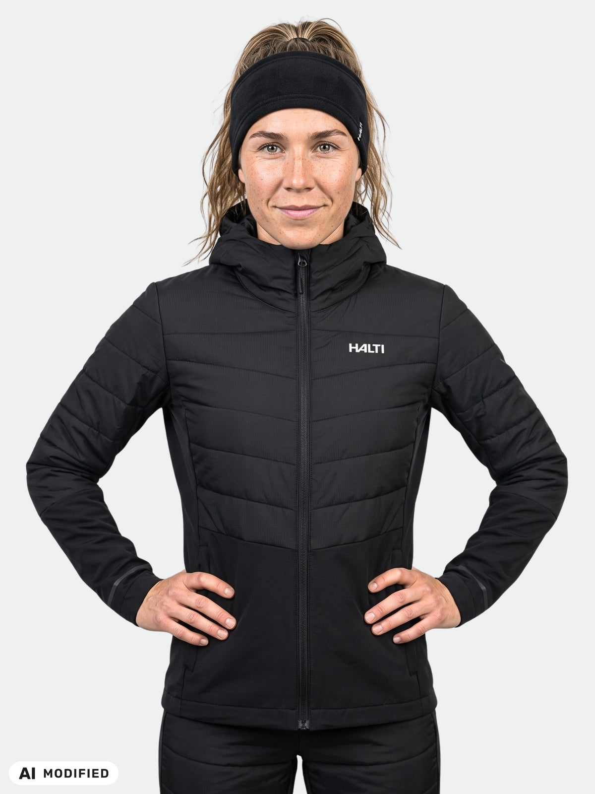 Woman wearing a black, hooded Halti Valimo Hybrid Insulation Jacket Women’s with her hands on her hips.