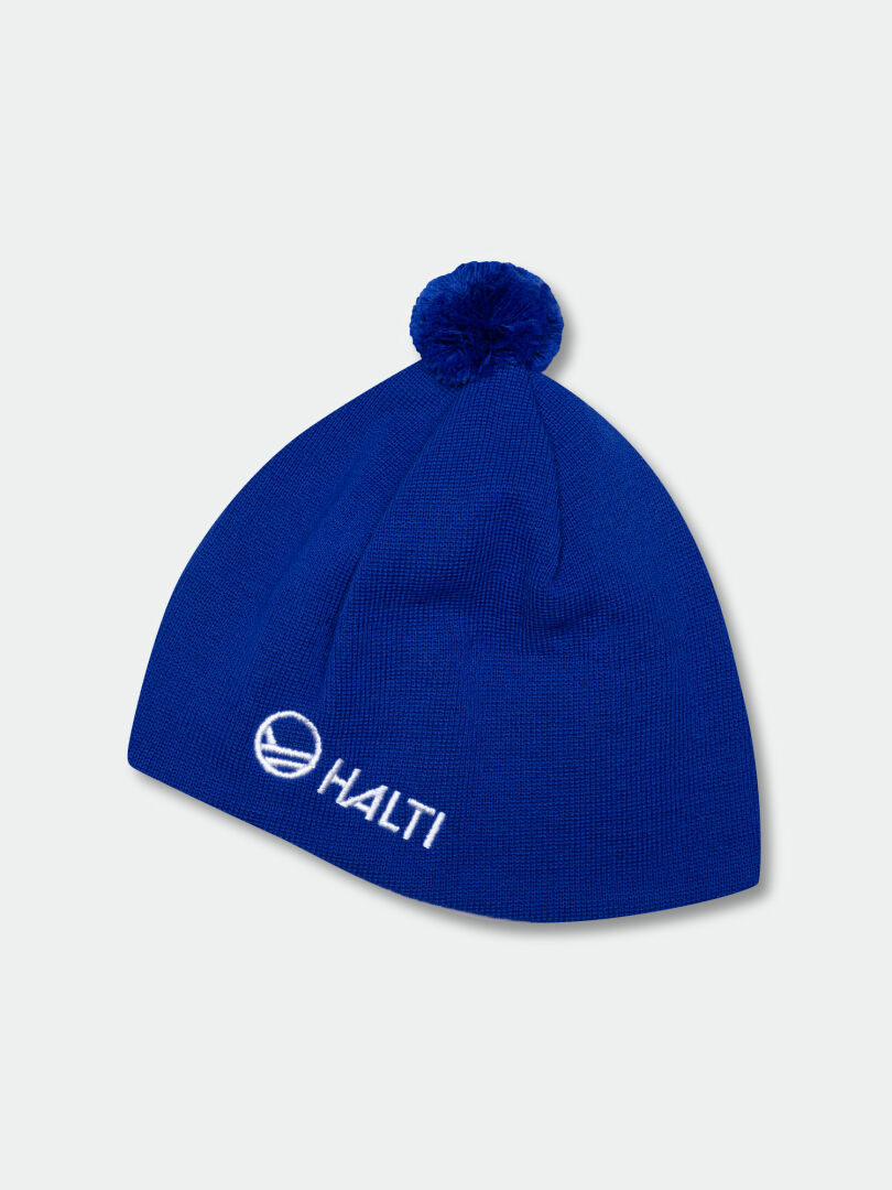 Halti Peesi Beanie: Blue Merino wool knit with pom-pom and white embroidered HALTI logo on the front.