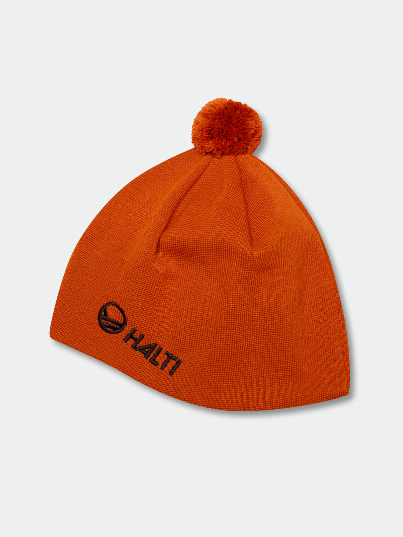 The Halti Peesi Beanie is an orange knit hat with Stormwall® and pom-pom, ideal for skiing. Halti logo on front.