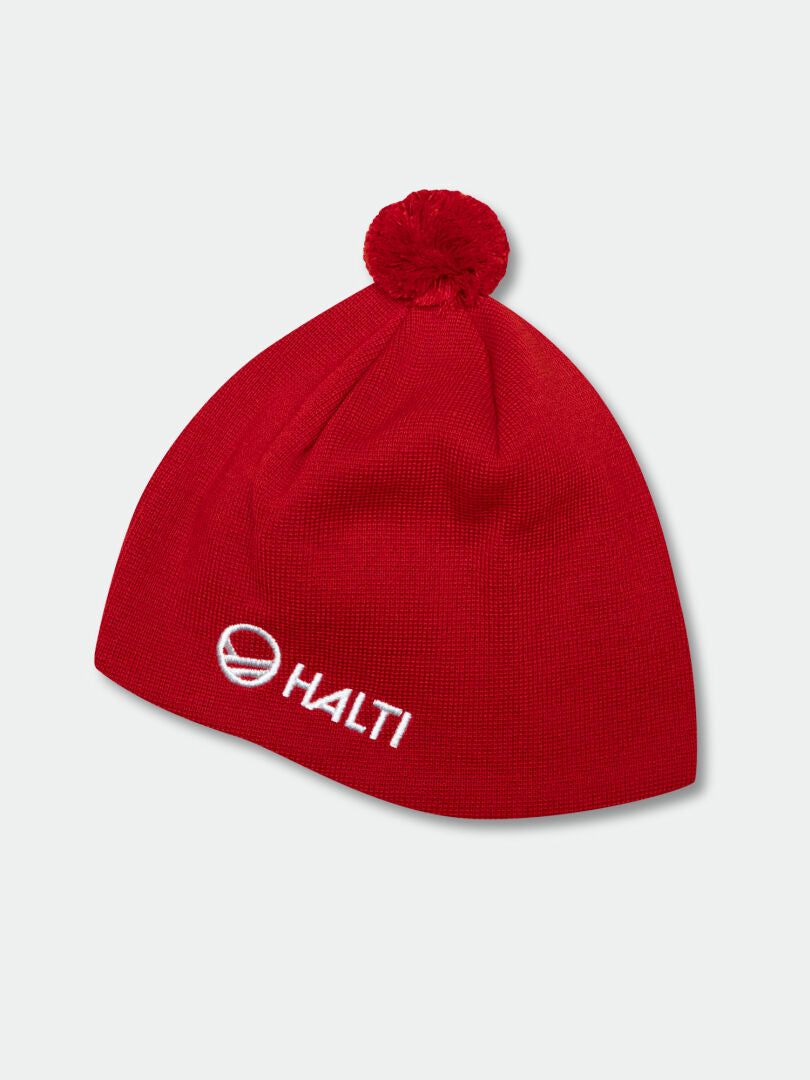 The Peesi Beanie by Halti is a red Merino wool knit with a pom-pom and white embroidered Halti logo.