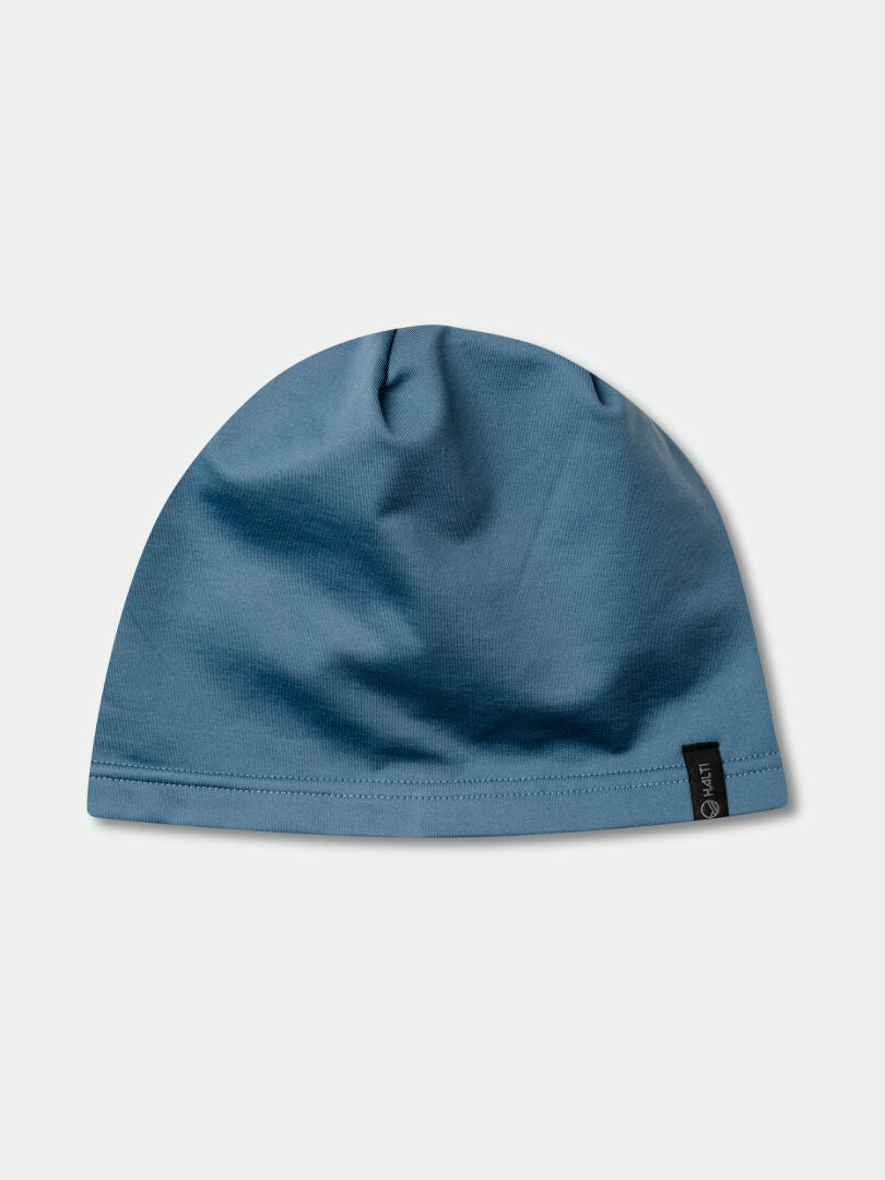 The Halti Loiva Beanie is a plain blue technical knit with a small black tag, shown on a light gray background.