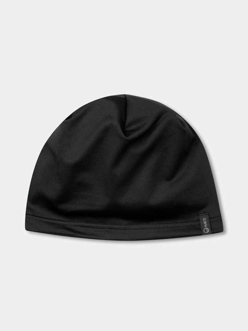 The Halti Loiva Beanie, a plain black knit made from recycled fibers, lays flat on a light gray surface with a black tag.