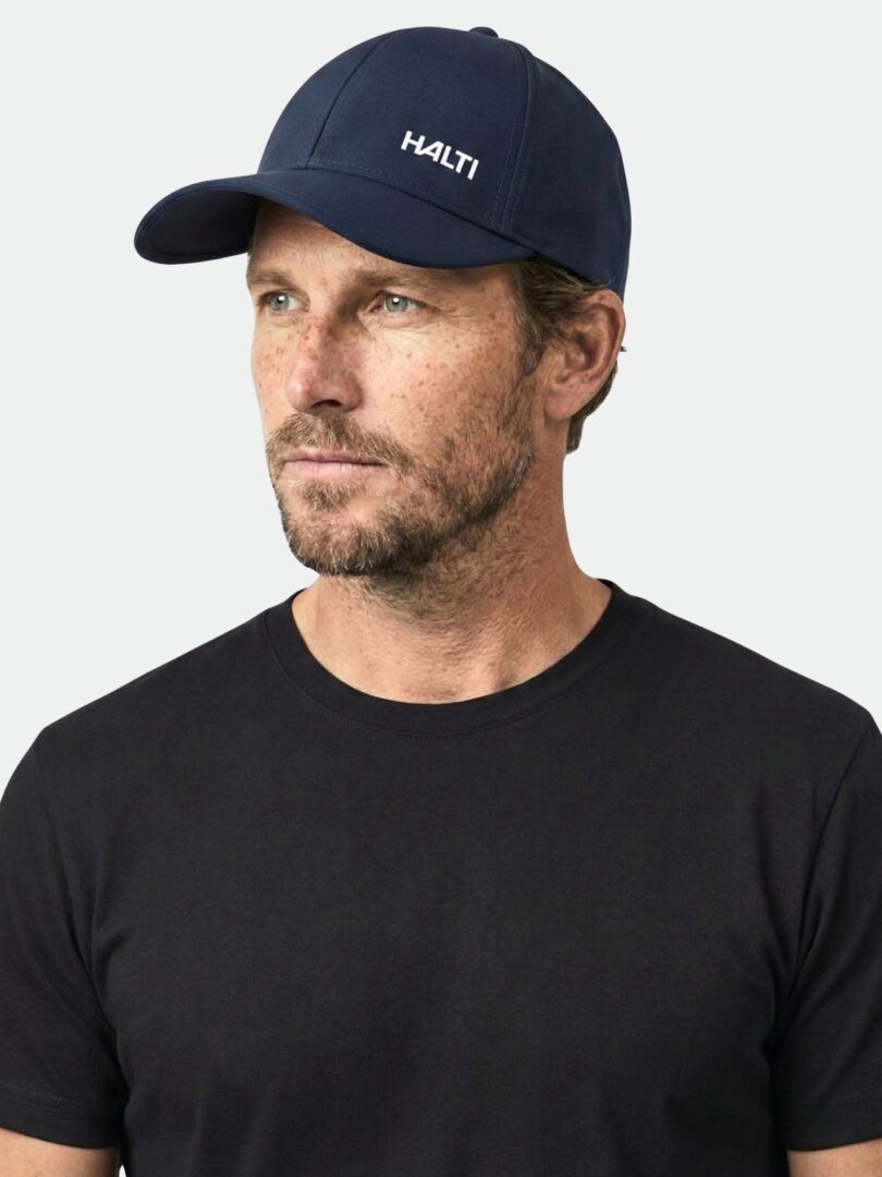 Man in a navy Mattas Baseball Cap by Halti and black t-shirt, looking left against a plain background.